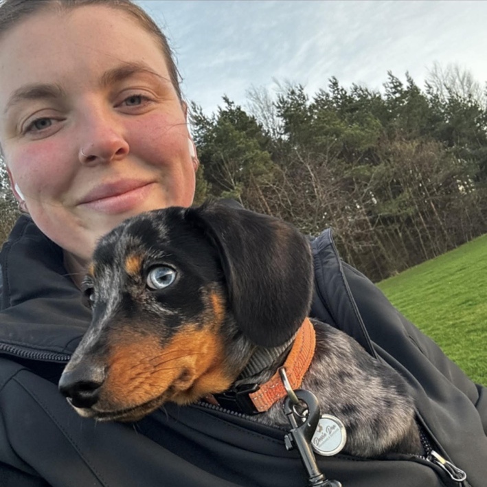 Katie outdoors with a dapple dachshund